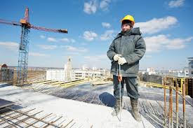 Construction worker standing on job site during wind chill.