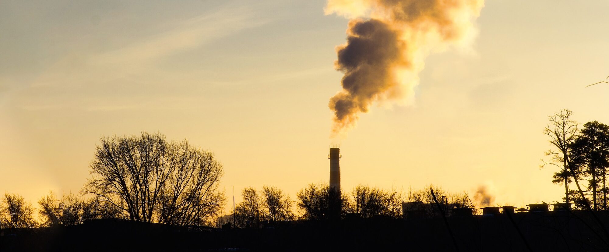 Sunset view of factory emissions polluting the atmosphere. Environmental pollution from factories at sunrise