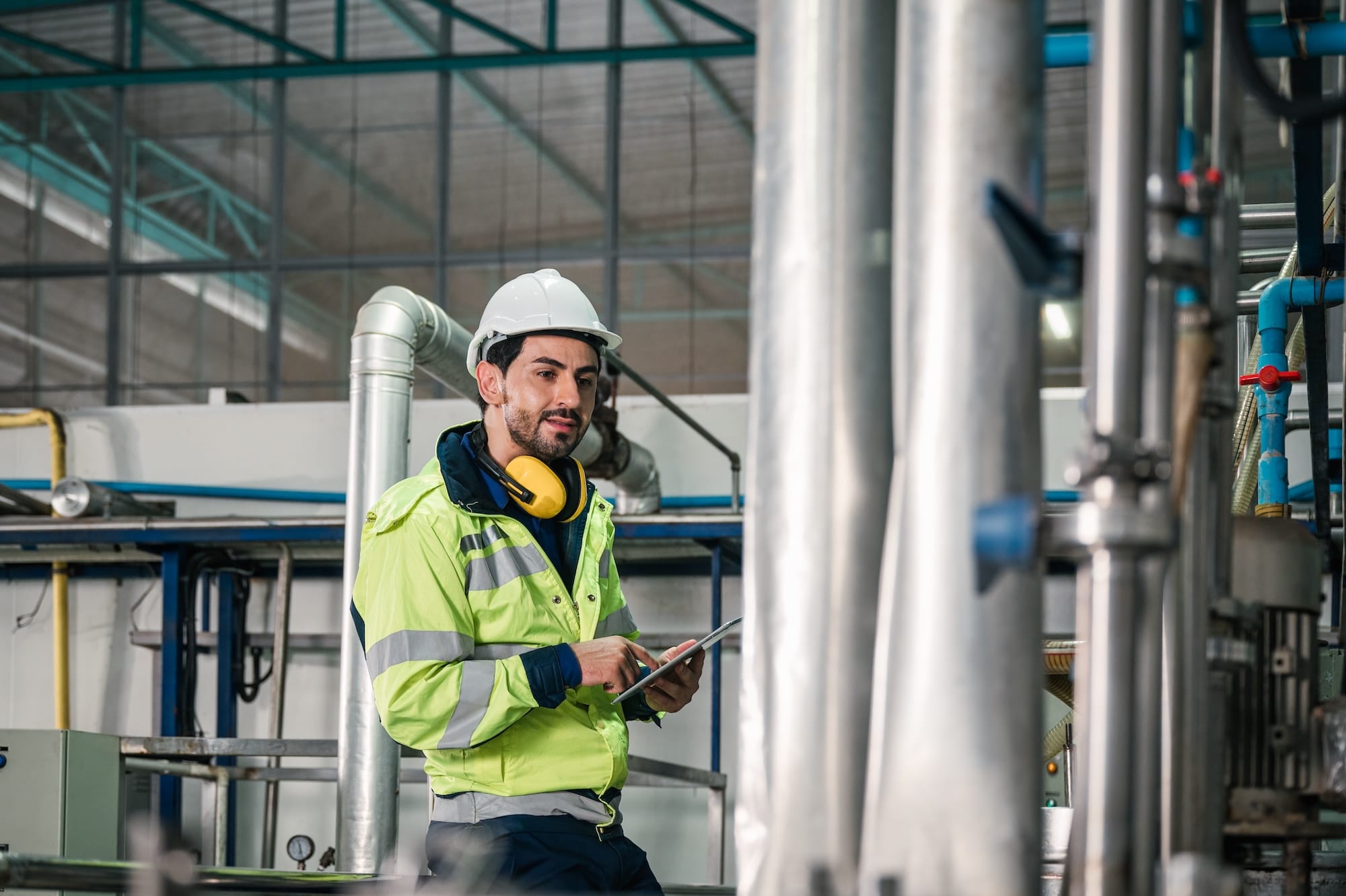 Man in safety vest with tablet in manufacturing plant