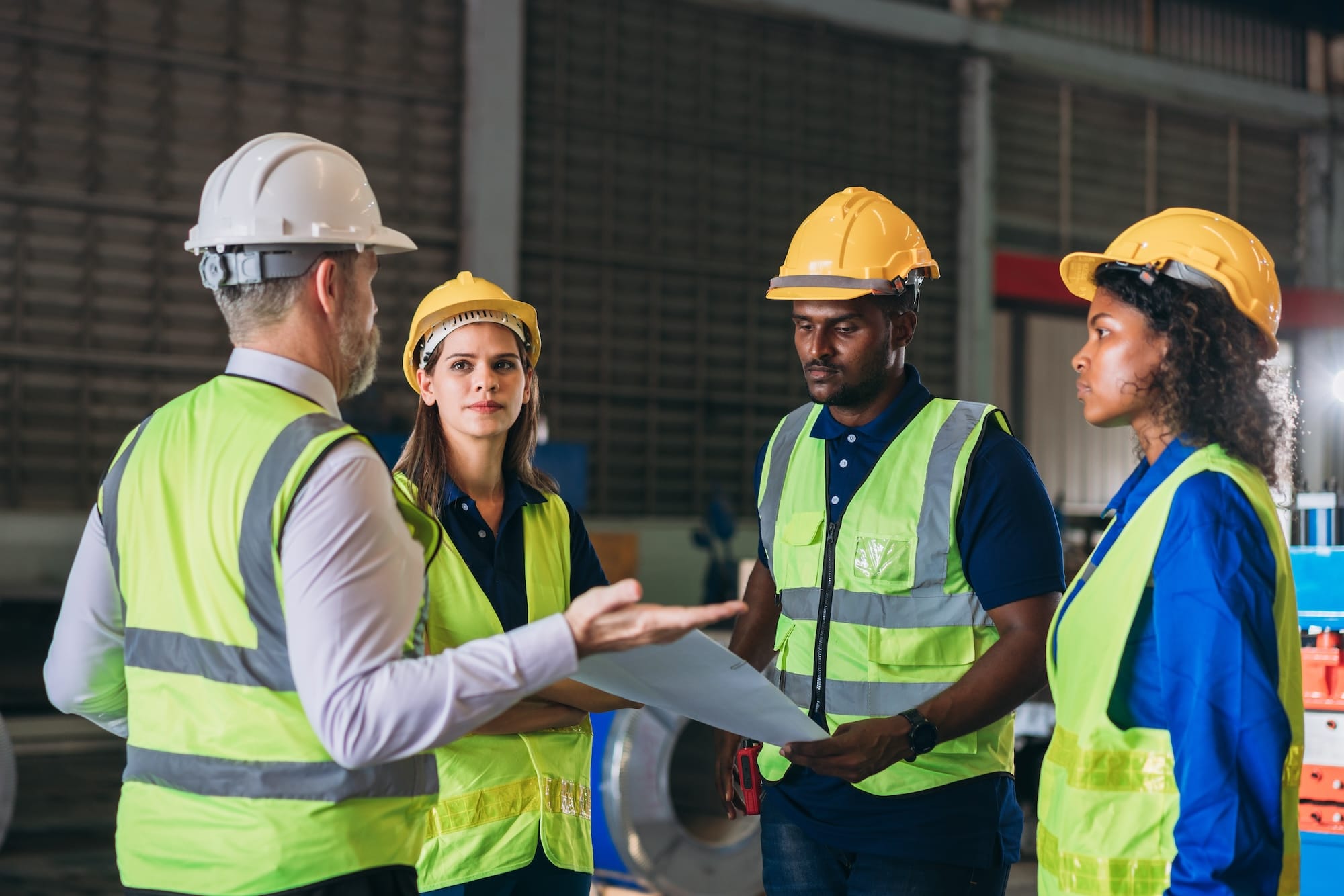 Workers in hard hats and safety vests conducting a safety committee meeting